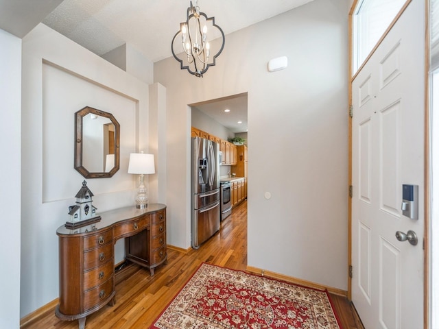 foyer with baseboards, a notable chandelier, and light wood finished floors