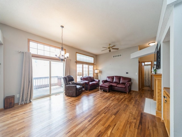 living room with visible vents, wood finished floors, and ceiling fan with notable chandelier