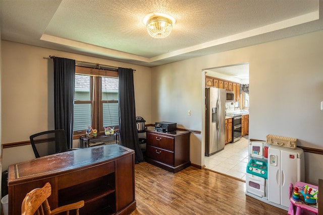 office area with a textured ceiling, light wood-style flooring, a sink, a raised ceiling, and a notable chandelier