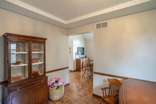 corridor featuring wood finished floors, visible vents, and baseboards