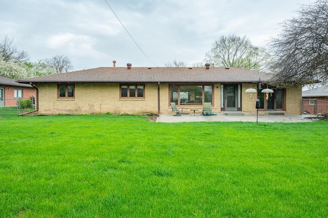 back of house with brick siding, a lawn, and a patio area