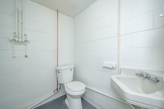 bathroom featuring toilet, concrete floors, and a sink