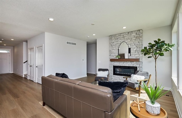 living area with visible vents, baseboards, wood finished floors, and a fireplace