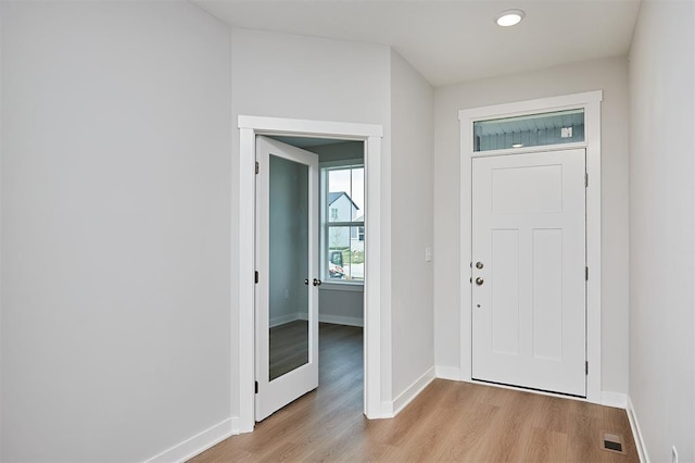 foyer entrance with baseboards, visible vents, and light wood finished floors
