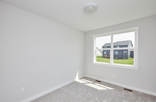 carpeted empty room featuring visible vents and baseboards