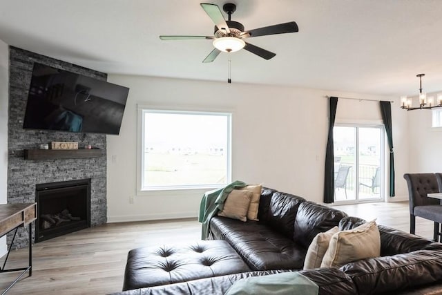 6635 NE 9th Ct, Des Moines, IA 50313 - living room with baseboards, light wood-type flooring, ceiling fan with notable chandelier, and a stone fireplace
