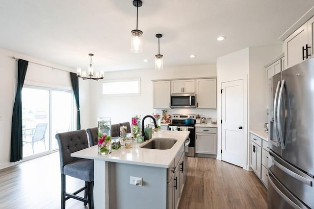 6635 NE 9th Ct, Des Moines, IA 50313 - kitchen with a sink, a kitchen bar, light countertops, appliances with stainless steel finishes, and wood finished floors