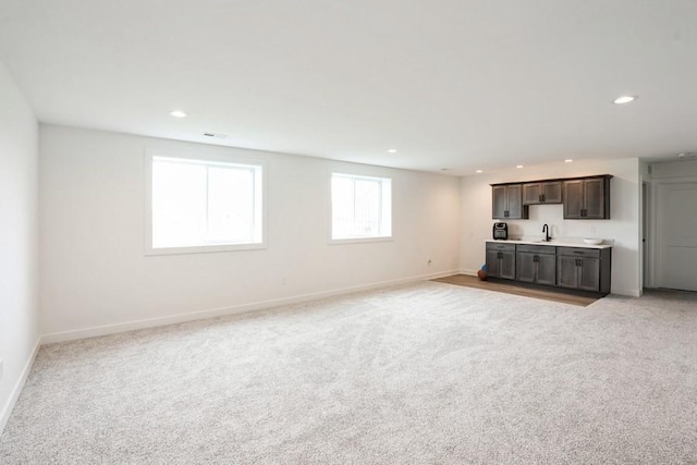 6635 NE 9th Ct, Des Moines, IA 50313 - unfurnished living room with recessed lighting, a sink, light colored carpet, and baseboards