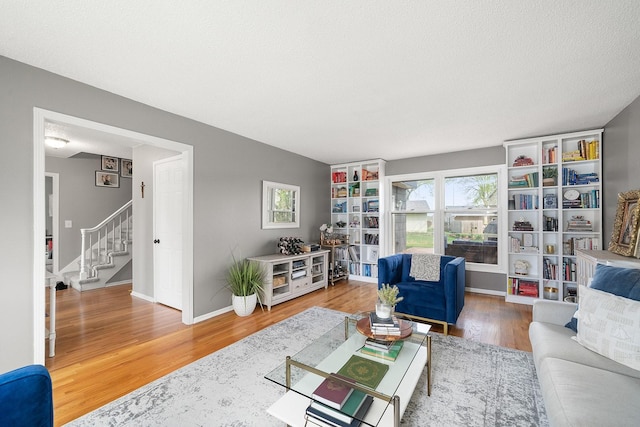 living area featuring baseboards, wood finished floors, and stairs