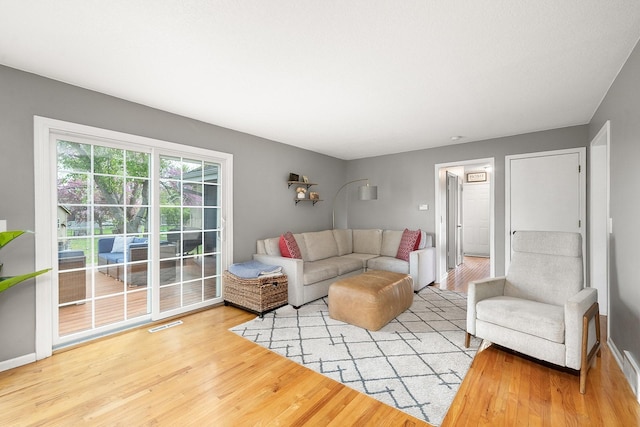 living area featuring baseboards, visible vents, and wood finished floors