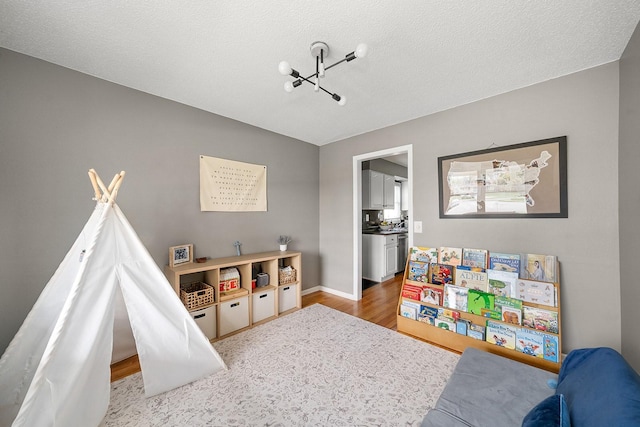 game room with baseboards, wood finished floors, and a textured ceiling