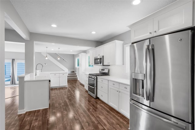 4010 Fagen Dr, Des Moines, IA 50310 - kitchen with stainless steel appliances, a peninsula, dark wood finished floors, light countertops, and white cabinetry