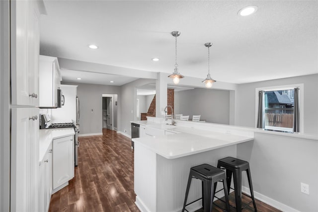 kitchen with a kitchen breakfast bar, stainless steel appliances, white cabinets, and a sink