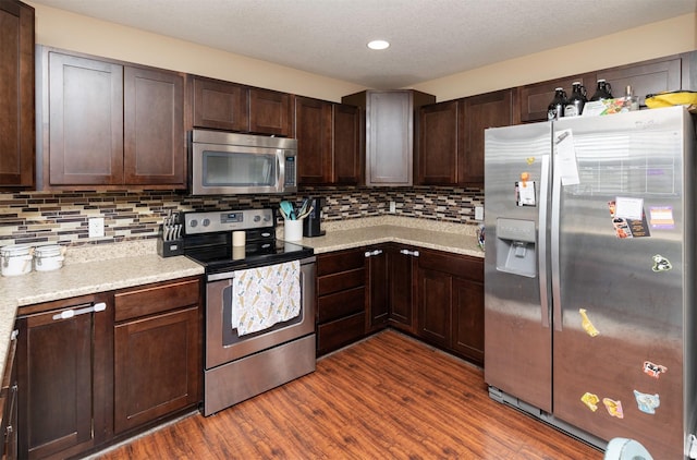 2884 Park Pl, Norwalk, IA 50211 - kitchen with stainless steel appliances, light countertops, dark wood-style flooring, backsplash, and dark brown cabinetry