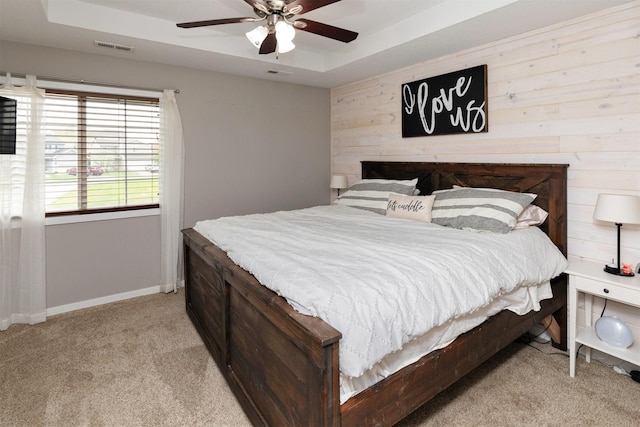 2884 Park Pl, Norwalk, IA 50211 - bedroom with a tray ceiling, light carpet, wooden walls, baseboards, and ceiling fan