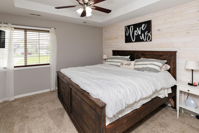 2884 Park Pl, Norwalk, IA 50211 - bedroom featuring light colored carpet, a tray ceiling, wood walls, and a ceiling fan