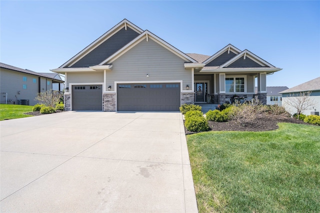 craftsman house with concrete driveway, stone siding, a front yard, an attached garage, and central AC unit