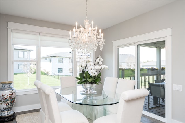 dining area with baseboards, wood finished floors, and a chandelier