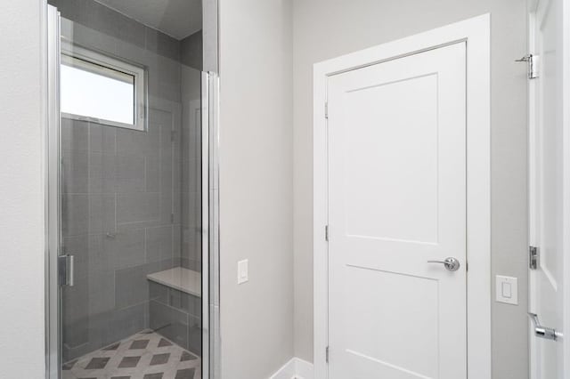 full bath with a shower stall and baseboards