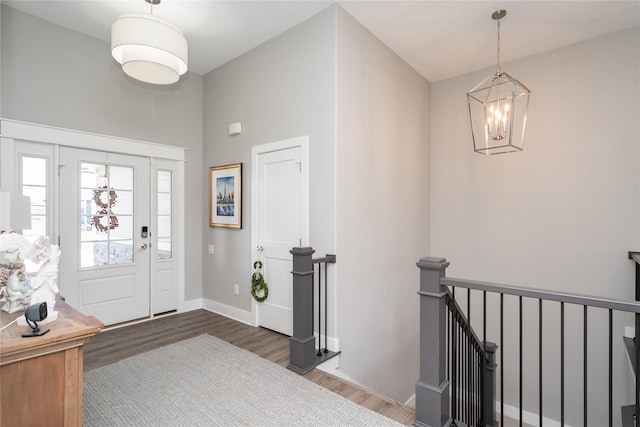 foyer featuring wood finished floors, baseboards, a notable chandelier, and a high ceiling