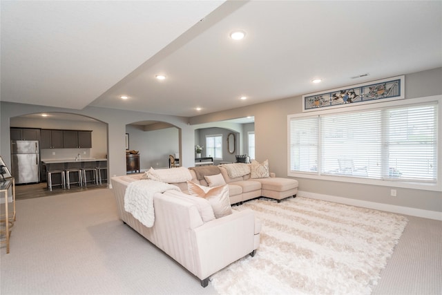 carpeted living area with baseboards, recessed lighting, and arched walkways