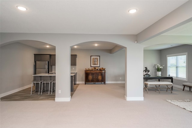 living area with light colored carpet, baseboards, recessed lighting, and arched walkways