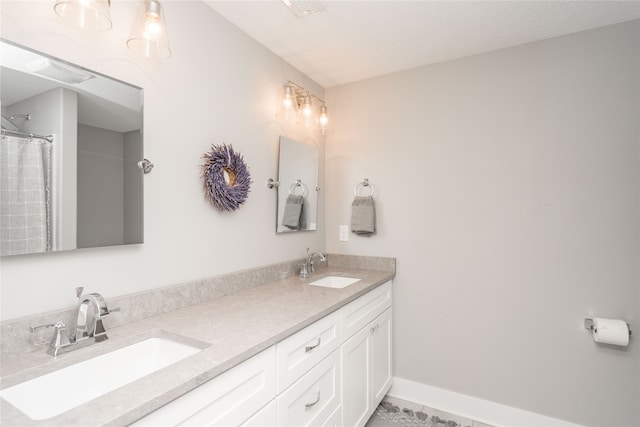 full bath featuring double vanity, tile patterned floors, baseboards, and a sink