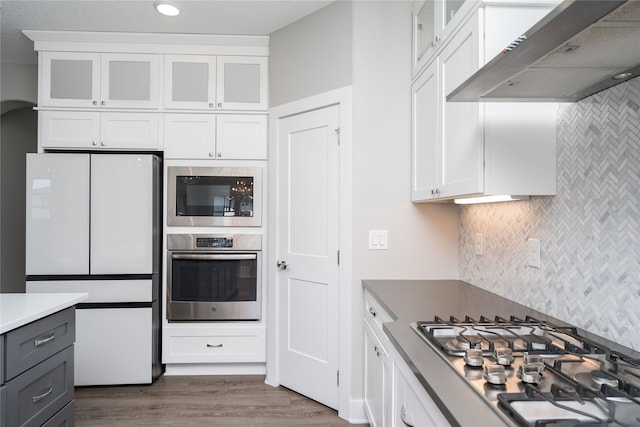 kitchen with white cabinetry, exhaust hood, and appliances with stainless steel finishes