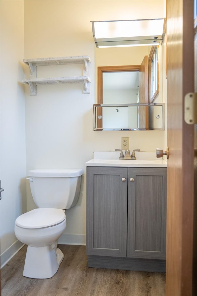180 1st St, Gilbert, IA 50105 - half bathroom featuring wood finished floors, toilet, vanity, and baseboards