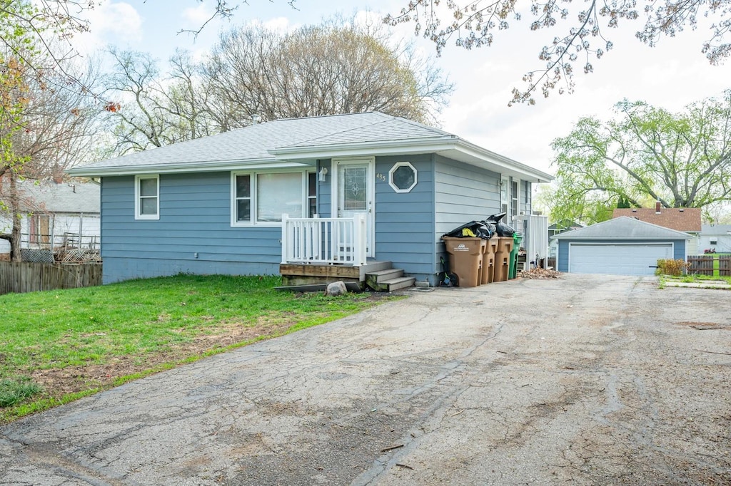 435 N 2nd St, Carlisle, IA 50047 - ranch-style home featuring roof with shingles, a detached garage, a front yard, and an outbuilding