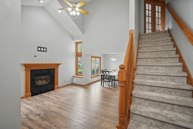 1410 Alderwood Dr, Altoona, IA 50009 - staircase featuring a fireplace, wood-type flooring, baseboards, high vaulted ceiling, and a ceiling fan