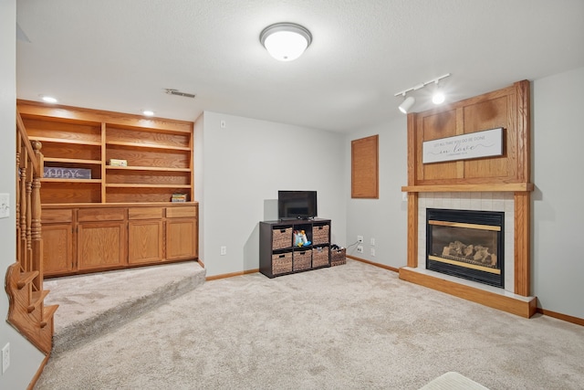 1410 Alderwood Dr, Altoona, IA 50009 - unfurnished living room featuring rail lighting, carpet, a tiled fireplace, and baseboards