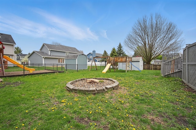 1410 Alderwood Dr, Altoona, IA 50009 - view of yard with a storage unit, a playground, a fenced backyard, and an outdoor fire pit