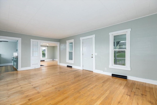 unfurnished living room with hardwood / wood-style floors and baseboards