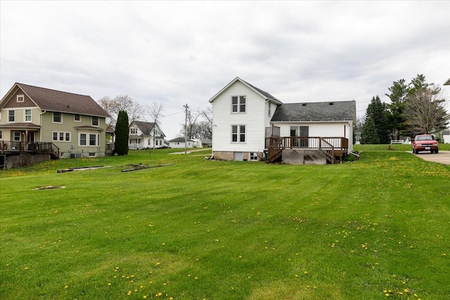 rear view of house with a wooden deck, a residential view, and a lawn