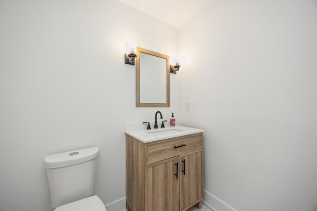 half bathroom with toilet, vanity, and baseboards