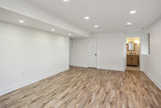 finished below grade area with a sink, light wood-type flooring, recessed lighting, and baseboards