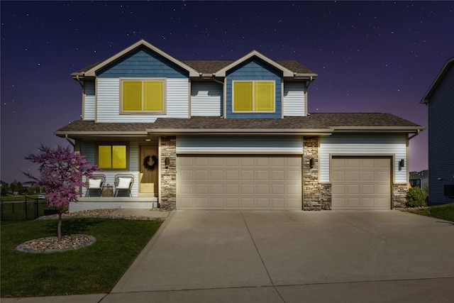 view of front of home featuring a yard, stone siding, driveway, roof with shingles, and an attached garage