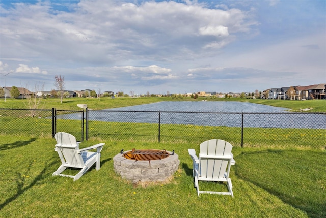 view of yard featuring a fire pit, fence, a residential view, and a water view