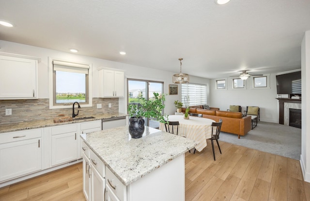 kitchen with white cabinetry, a sink, ceiling fan, a kitchen island, and backsplash