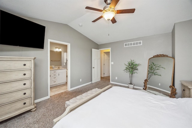 bedroom featuring ensuite bath, light colored carpet, baseboards, visible vents, and lofted ceiling