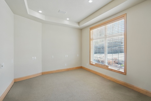 carpeted empty room featuring baseboards, recessed lighting, a raised ceiling, and visible vents