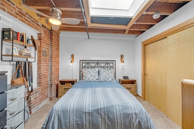 carpeted bedroom with visible vents, a ceiling fan, a closet, and brick wall