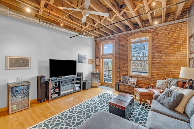 living area featuring wood finished floors, brick wall, baseboards, visible vents, and a ceiling fan