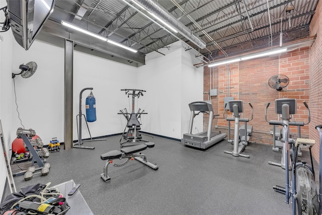 gym featuring brick wall and a high ceiling