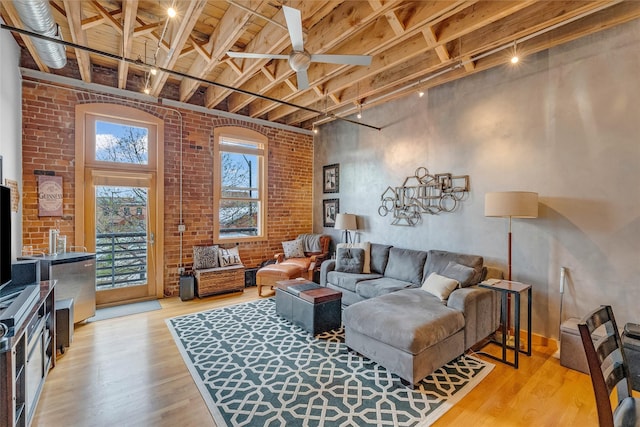 living area with ceiling fan, light wood-style floors, brick wall, and wood ceiling