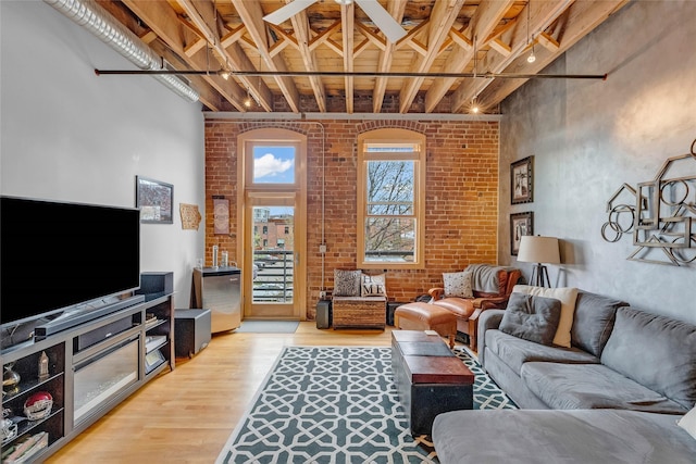 living area with brick wall and light wood-style flooring