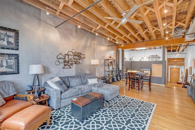 living room featuring beam ceiling, wood finished floors, and ceiling fan