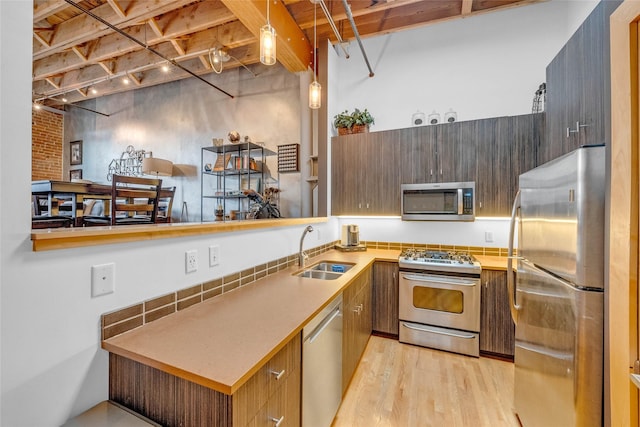 kitchen featuring light wood finished floors, modern cabinets, a sink, stainless steel appliances, and light countertops