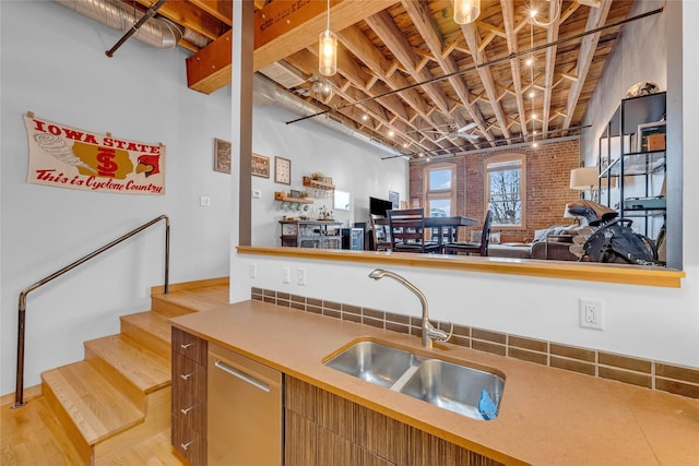 kitchen with light countertops, light wood finished floors, a sink, pendant lighting, and open floor plan